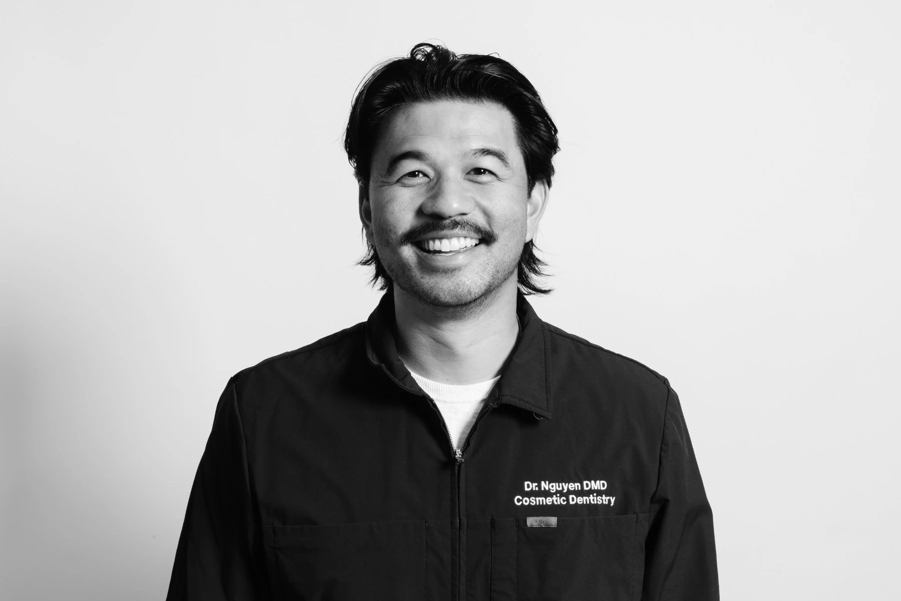 Black-and-white portrait of Dr. Khoa Nguyen in a black dental jacket